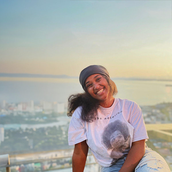 Fasika sitting down and smiling warmly with a skyline view in the back